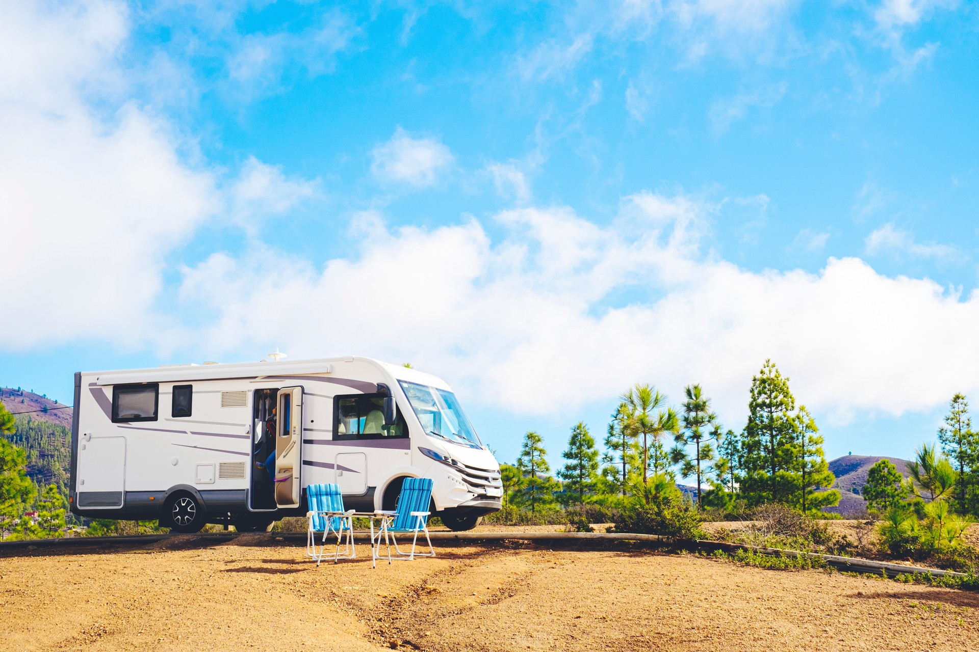 Beautiful tourism camper van campsite in the nature. Travel and rv renting vehicle vacation. Vanlife and wanderlust concept with modern motorhome parked in the nature with blue sky background